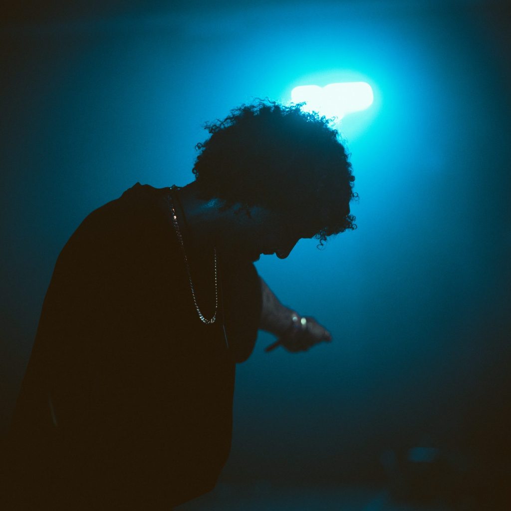 Singer silhouette with a microphone on an artistic stage background, representing TLX Talent Agency.